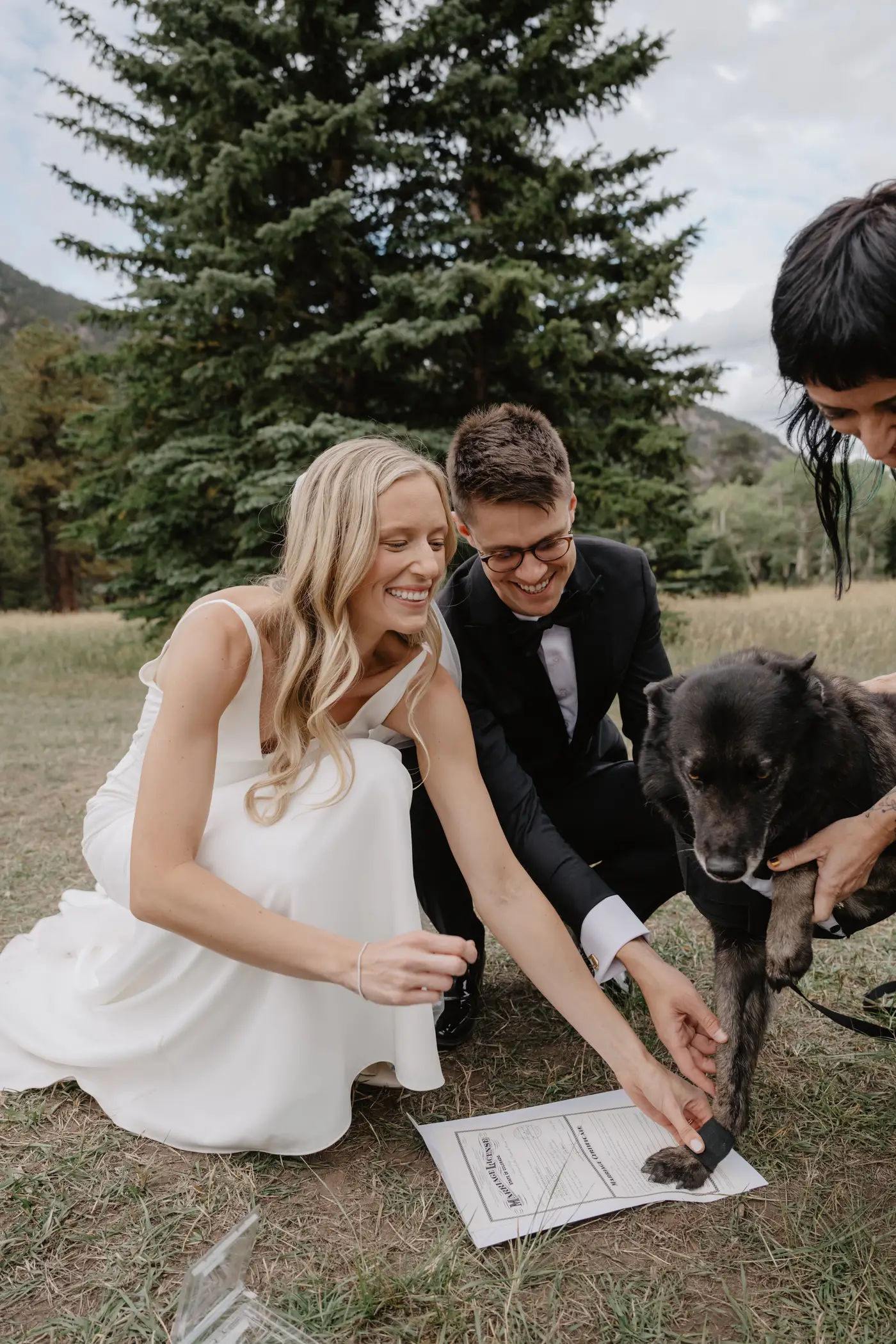 Billie and Nick helping Jax add his paw print to their marriage certificate